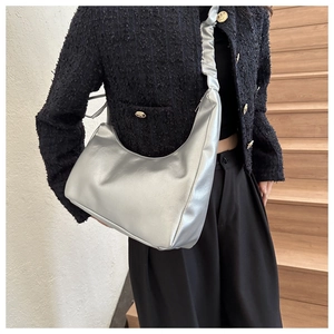 Detail of silver metallic crescent bag with wrinkled shoulder strap and smooth texture