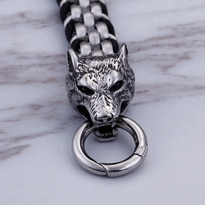 Macro shot of stainless steel wolf head charm with ring clasp on black braided bracelet