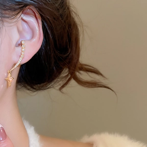 Detailansicht eines goldenen Stern-Ohrrings mit funkelnden Zirkoniasteinen am Modellohr