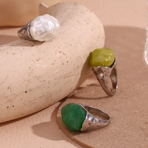 Detail of three stainless steel rings with irregular white and green acrylic stones