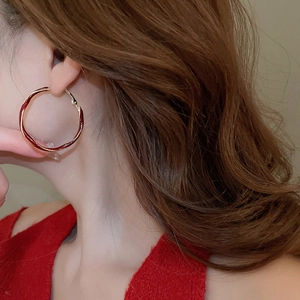 Close-up of model wearing vintage red enamel hoop earrings with metallic gold trim edges