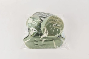 Detailed set of green silicone baby feeding utensils packaged in a protective clear polybag