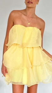 Close-up of bright yellow strapless organza dress with layered ruffle cake skirt detail