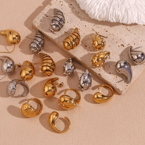 Flat lay of vintage gold and silver teardrop earrings and textured rings on stone background