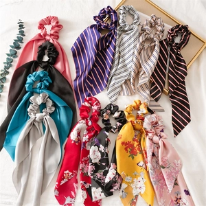 Various satin ribbon scrunchies in solid, striped, and floral patterns on white linen