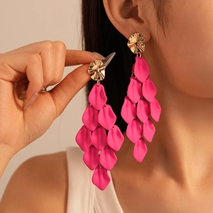 Close-up of pink acrylic petal tassel earrings with gold irregular studs on model