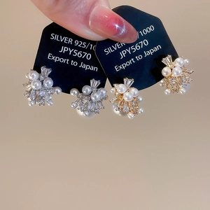 Macro detail of 925 silver stud earrings with cluster pearls and sparkling zircons