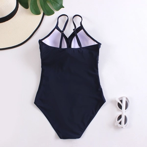 Detail view of navy blue one-piece swimsuit with cross-back straps and sun accessories