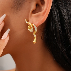 Close-up of golden snake-shaped stud earring with micro-set rhinestones on model