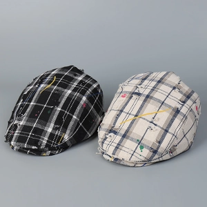 Close-up of distressed plaid flat caps with colorful paint splatter and frayed details