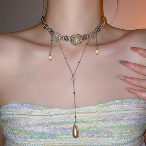 Detail of layered necklace with gold embossed medallion and amber teardrop charm