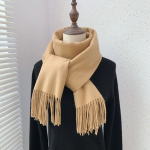 Detailed view of camel faux cashmere scarf featuring elegant tassel edges on a mannequin