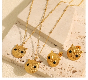 Detailed close-up of golden owl jewelry set with black stones on a stone surface