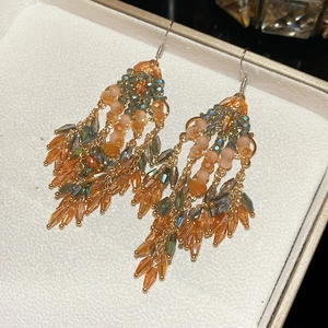 Detail of vintage bohemian drop earrings with orange and green crystal tassels in a box
