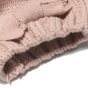 Soft pink knit winter hat with bow detail for kids, cozy texture on white background