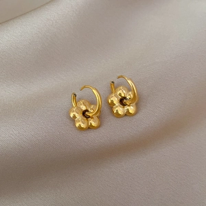Pendientes de aro con flor en acero de titanio dorado sobre fondo de seda elegante