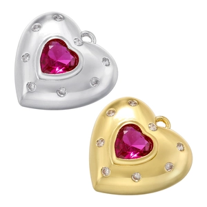 Detail of gold and silver heart pendants with red crystals and small white gemstones