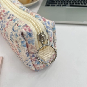 Detail of silver circular zipper on a floral corduroy pouch with pixel art flower patterns