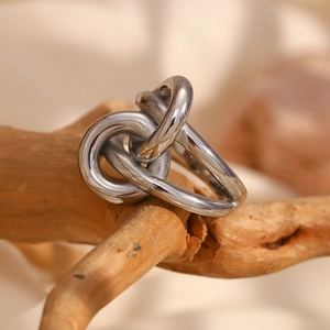 Close-up of a silver knot-shaped stainless steel ring hanging on a wooden branch