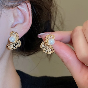 Close-up of hollow butterfly stud earrings with white pearl and sparkling rhinestones