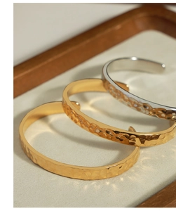 Dettaglio di bracciali martellati in oro e argento su un vassoio da esposizione in legno