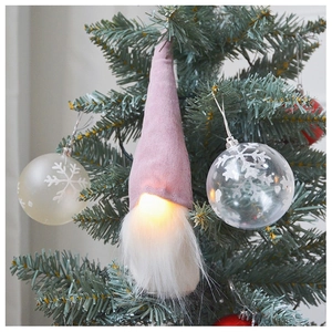 Close-up of a pink glowing gnome ornament hanging on a green Christmas tree branch