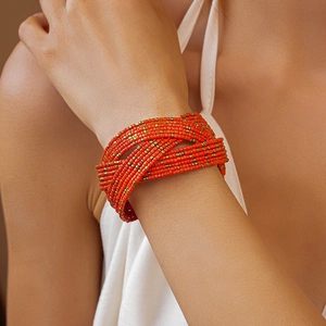 Close-up of multi-layer orange seed bead bracelet with vintage gold metal accents