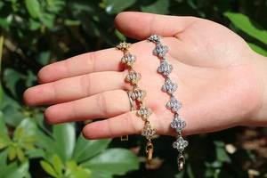 Elegant gold and silver clover bracelets with sparkling zircons worn on a wrist