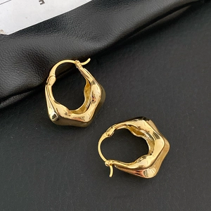 Vue macro des boucles d'oreilles créoles dorées à texture lave sur cuir noir