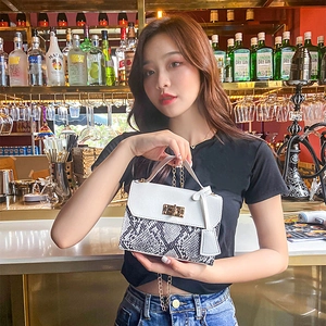 White snakeskin pattern handbag with gold chain handle shown on a fashion model