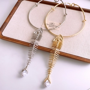 Detail of gold and silver fishbone necklaces with rhinestones and pearl drops on a tray