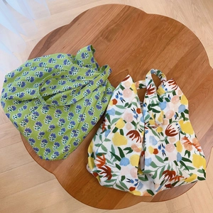 Floral cotton tote bags in green and beige displayed on a wooden flower coffee table
