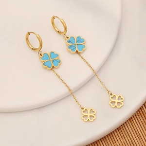 Detail of gold clover earrings with blue marble stone dangling on white ceramic plate