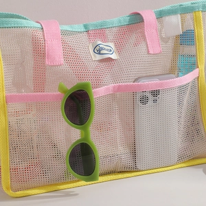Detail of large mesh beach tote bag with multi-pocket design and colorful trimmings