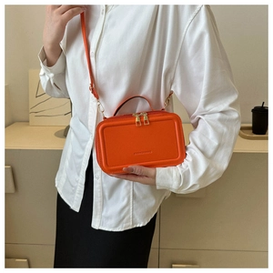 Detail of orange suitcase-style bag with double zippers and Fashion & Bag embossing