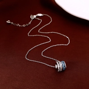 Detailed close-up of a silver cylinder pendant with blue and white zircon gemstones