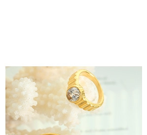 Gros plan d'une bague dorée ornée d'une pierre précieuse ronde sur corail blanc