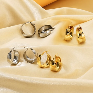 Detailed view of wide curved stainless steel hoop earrings in gold and silver finishes