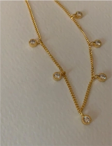 Macro view of gold dainty chain necklace featuring circular cubic zirconia pendants