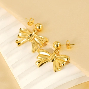Polished 18k gold plated stainless steel bow earrings displayed on a white stand