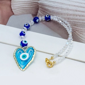 Detailed view of blue evil eye beads and heart-shaped pendant with golden clasp