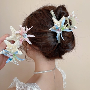 Close-up of starfish hair clip with blue flowers and crystals for summer beach styles