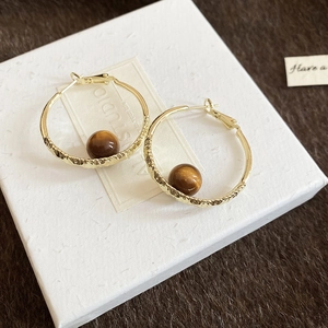 Detail view of gold hammered hoop earrings with suspended brown shimmering bead pendants