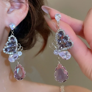 Macro shot of butterfly drop earrings with purple zircon stones on a model's ear