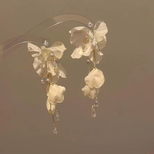 Close-up of elegant white fabric flower tassel earrings with dangling crystals