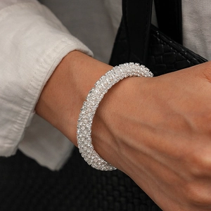 Gros plan d'un large bracelet argenté serti de strass brillants sur le poignet d'une femme