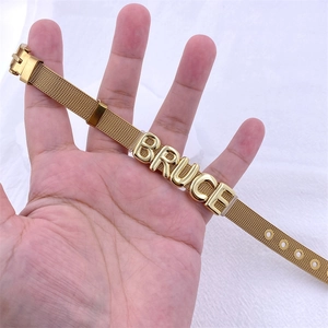 Golden mesh strap bracelet with customized BRUCE letter sliders worn on wrist detail