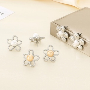 Détail macro de boucles d'oreilles élégantes en acier doré 18K avec pétales et perles