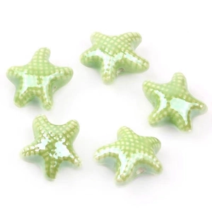 Detail view of five light green ceramic starfish beads with white dots for DIY jewelry