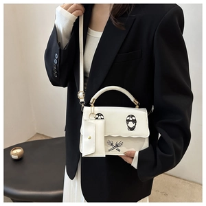 Close-up of white crossbody bag with black skull print and matching mini pouch detail